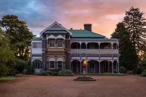 Historic two storey building sits against a pink and orange sunset