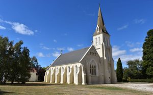 A soaring white church with a tall steeple and arched window, against a deep blue clear sky.