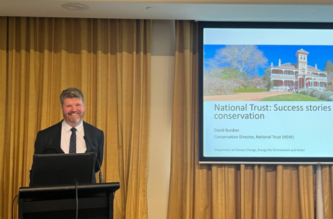 A man at a lectern delivering a presentation